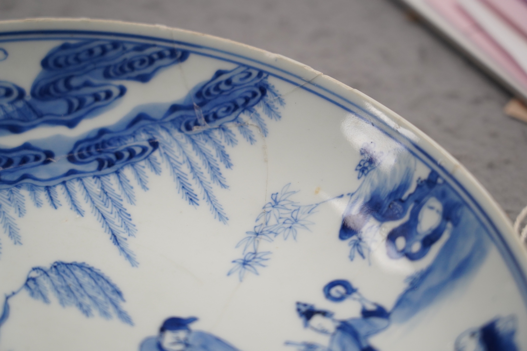 A Chinese blue and white dish, Kangxi period, broken and messily reglued